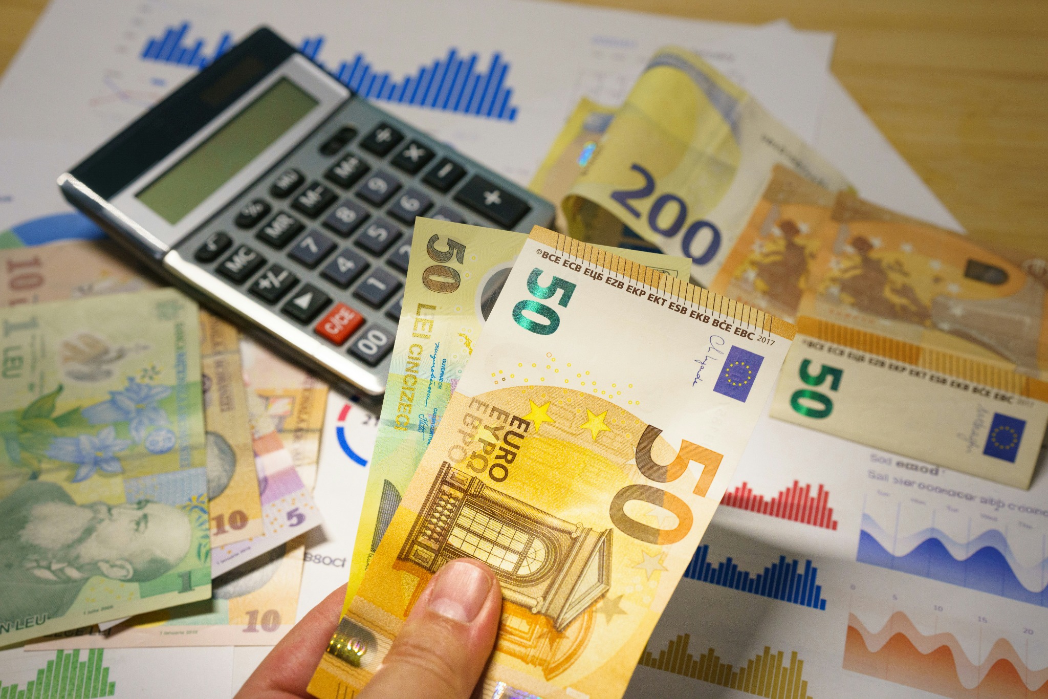 Calculadora y billetes de euro sobre documentos financieros para representar el coste de una página web